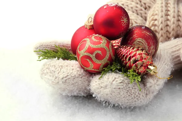 Female hands in mittens Christmas tree balls, on color background — Stock Photo, Image