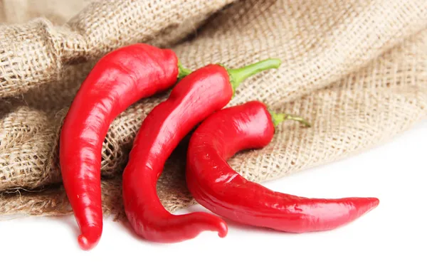 Pimentos de pimenta vermelha em pano de saco, isolados em branco — Fotografia de Stock