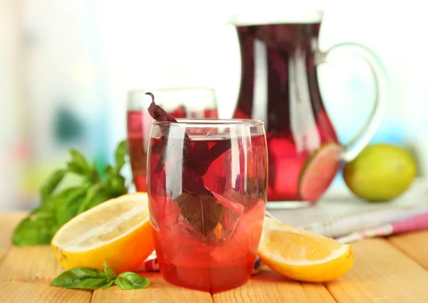 Limonada de manjericão vermelho em jarro e vidro, na mesa de madeira, no fundo brilhante — Fotografia de Stock
