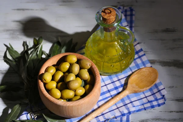 Aceite de oliva y aceitunas en un tazón sobre una mesa de madera servilleta —  Fotos de Stock