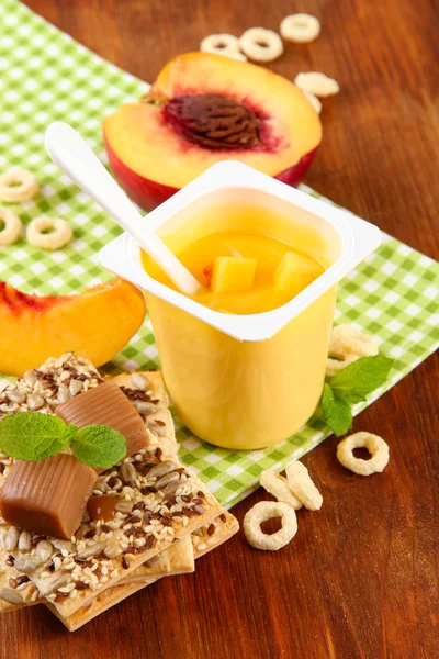 Yogurt saporito con pezzi di frutta fresca, biscotti e fiocchi, su sfondo di legno — Foto Stock
