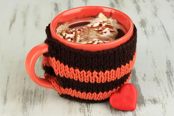 Cup with knitted thing on it on wooden table close up — Stock Photo, Image