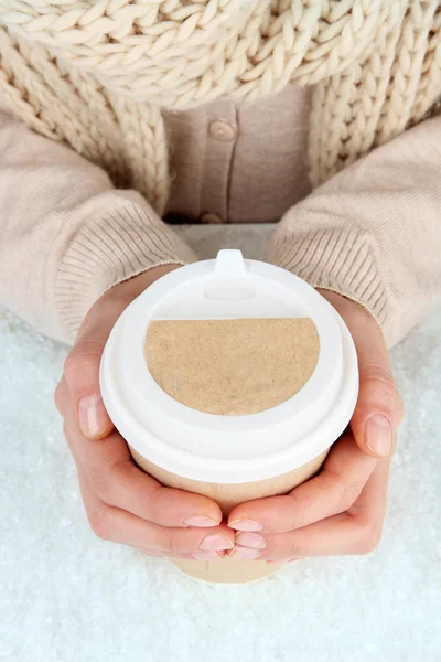 Hot drink in paper cup in hands with snow close up — Stock Photo, Image