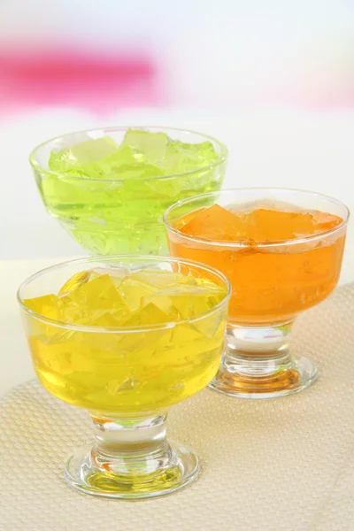 Tasty jelly cubes in bowls on table on light background — Stock Photo, Image