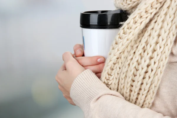 Hot drink in plastic glass in hands on bright background — Stock Photo, Image