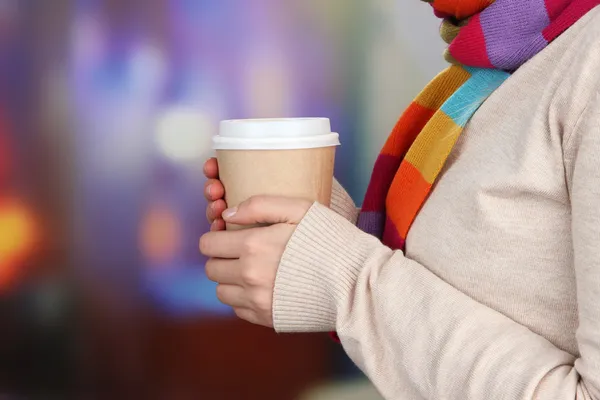 Bebida caliente en taza de papel en las manos sobre fondo brillante — Foto de Stock