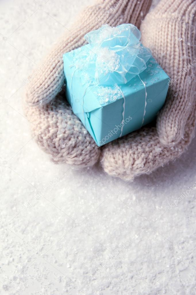 Female hands in mittens with gift box, on white background
