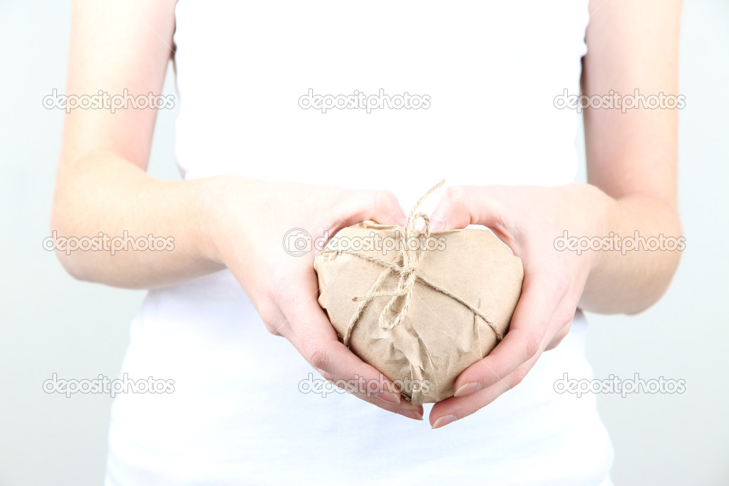 Woman hands holding a heart wrapped in brown kraft paper