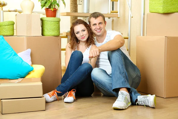 Pareja joven sentada en una casa nueva en el fondo de la escalera — Foto de Stock