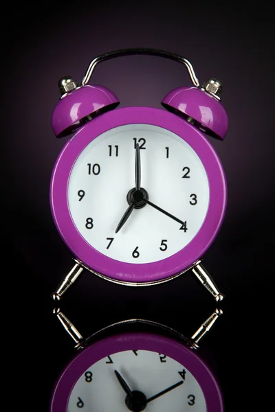 Purple alarm clock on dark purple background — Stock Photo, Image