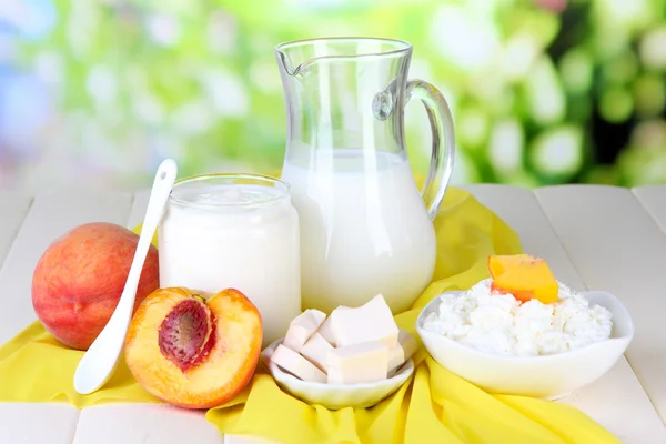 Fresh dairy products with peaches on wooden table on natural background — Stock Photo, Image