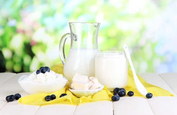 Fresh dairy products with blueberry on wooden table on natural background