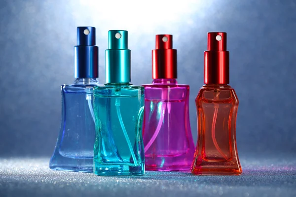 Perfume de las mujeres en hermosas botellas sobre fondo brillante —  Fotos de Stock