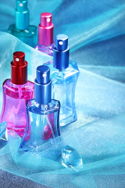 Perfume de mujer en hermosas botellas sobre fondo azul —  Fotos de Stock