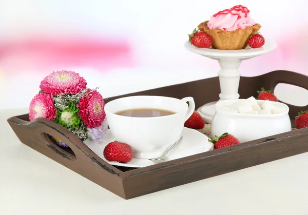 Cup of tea with cakes on wooden tray on table in room — Stock Photo, Image