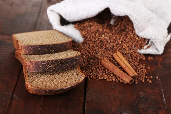 Doek zak met boekweit en brood op houten achtergrond — Stockfoto