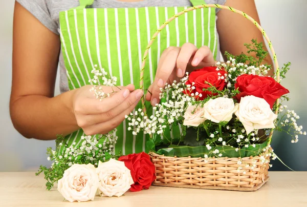 Florist makes flowers bouquet in wicker basket — Stock Photo, Image