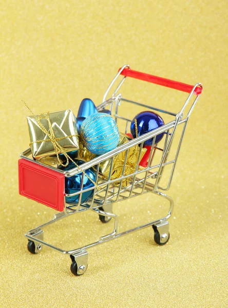 Regalos de Navidad en el carrito de la compra, sobre fondo dorado brillante — Foto de Stock