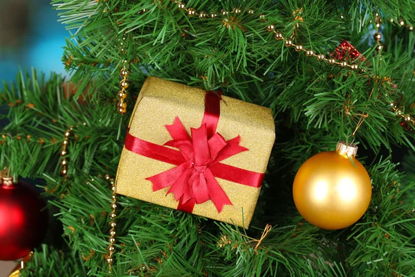 Gift on Christmas tree on room background — Stok fotoğraf