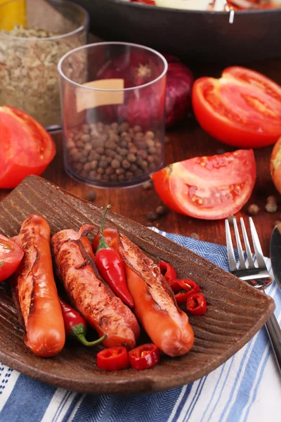 Delicious sausages with vegetables on plate on wooden table close-up — Stock Photo, Image