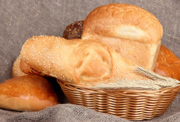 Gebackenes Brot im Weidenkorb auf Klette Hintergrund — Stockfoto