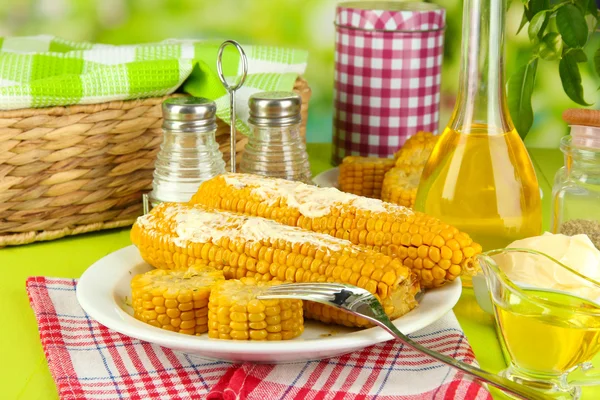 Aromatisierter gekochter Mais auf Teller auf Holztisch vor natürlichem Hintergrund — Stockfoto