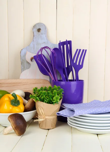 Plastic kitchen utensils in cup on wooden table — Stock Photo, Image