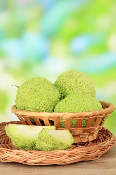 Osage orange Früchte (maclura pomifera) im Korb, auf Holztisch, auf Naturhintergrund — Stockfoto