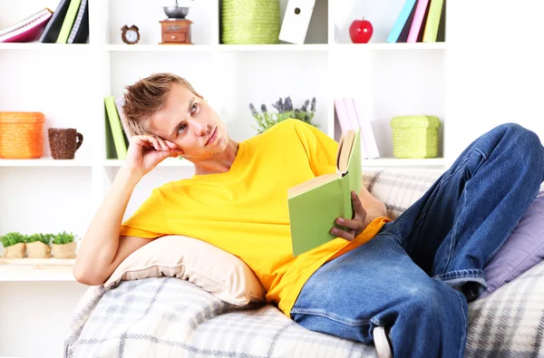 Jeune homme relaxant sur canapé avec livre — Photo