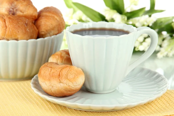 Tasty croissants and cup of coffee on table on white background — Stok fotoğraf