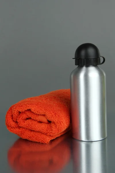 Sports bottle and towel on grey background — Stock Photo, Image