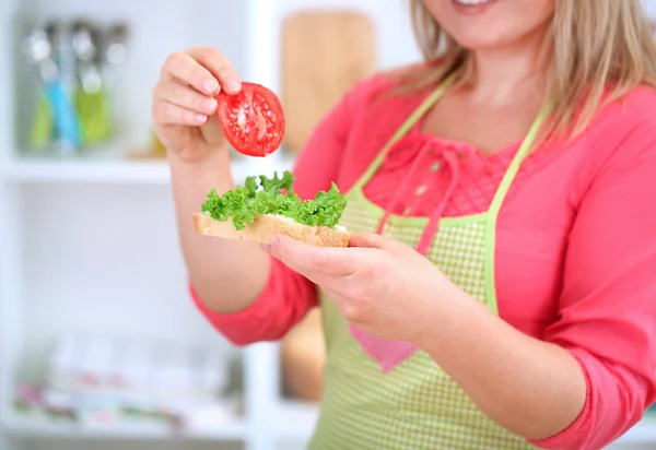 Happy smiling woman in kitchen preparing sandwich — Stock Photo, Image