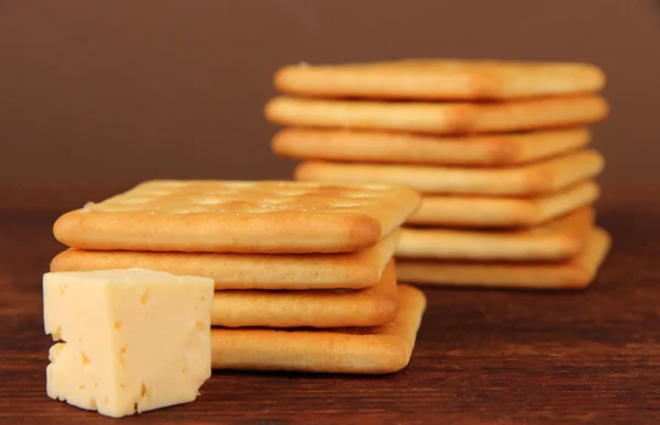 茶色の背景に木製のテーブルの上にチーズとおいしいクラッカー — ストック写真