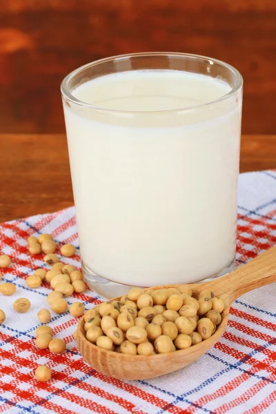 Habas de soja con vaso de leche sobre mesa sobre fondo de madera — Foto de Stock