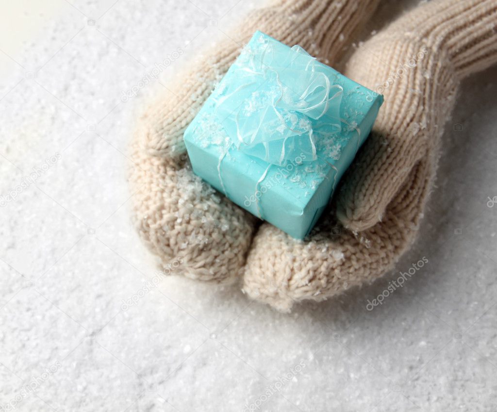 Female hands in mittens with gift box, on white background