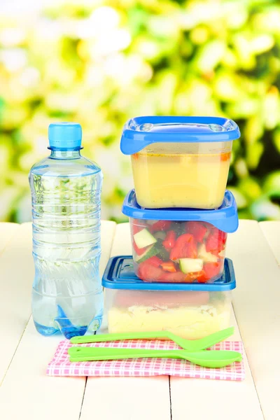Вкусный обед в пластиковых контейнерах, на деревянном столе на ярком фоне — стоковое фото