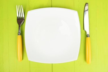 Plate and cutlery on wooden table close-up
