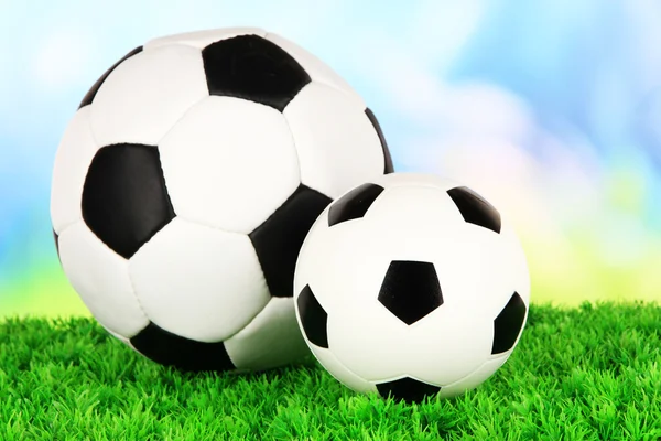 Soccer balls on green grass on bright background — Stock Photo, Image