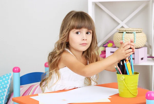 Bambina disegna seduto a tavola in camera su sfondo grigio parete — Foto Stock