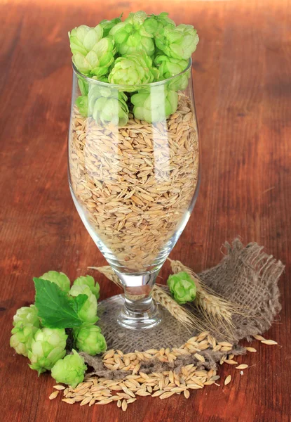 Glass of fresh green hops and barley, on wooden background — Stock Photo, Image