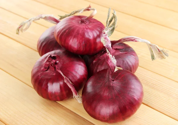 Fresh red onions on wooden table — Stock Photo, Image