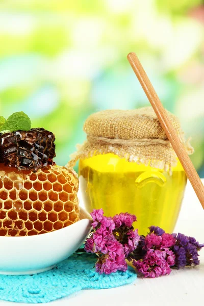 Doux nid d'abeilles dans un bol et banque avec du miel sur une table en bois sur fond naturel — Photo