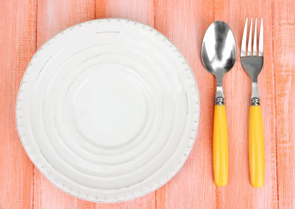 Plate and cutlery on wooden table close-up — Stock Photo, Image