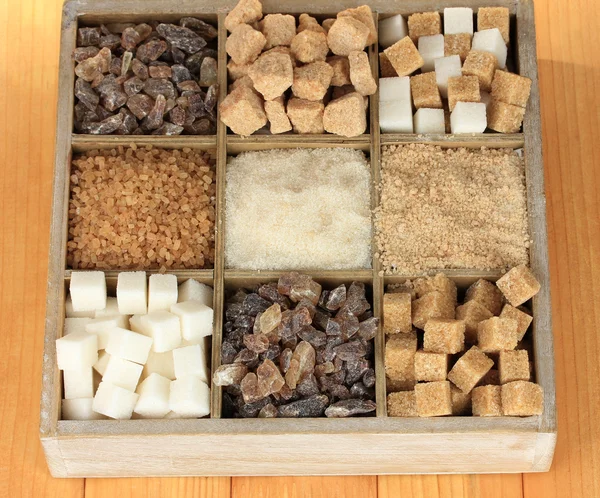 Verschillende soorten suiker in houten doos op tabel close-up — Stockfoto