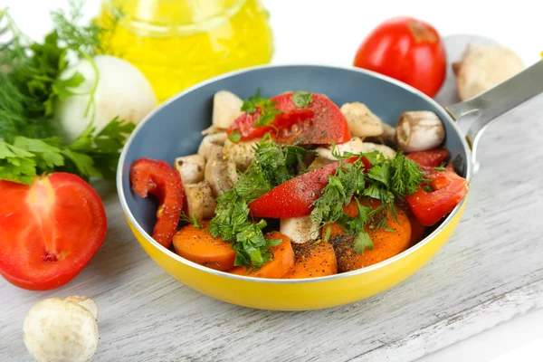 Légumes frais tranchés dans une casserole sur du bois isolé sur du blanc — Photo