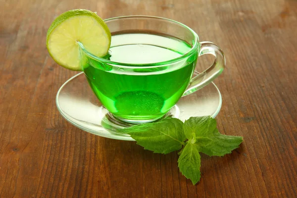 Transparent cup of green tea with lime and mint on wooden background — Stock Photo, Image