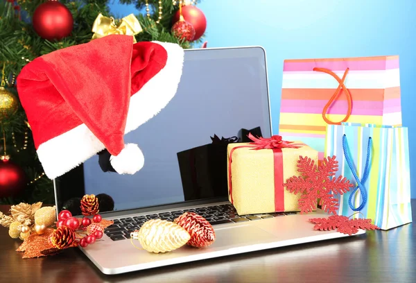 Portátil con regalos en la mesa sobre fondo azul — Foto de Stock