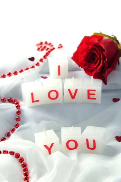 Candles with printed sign I LOVE YOU, on white fabric background — стоковое фото