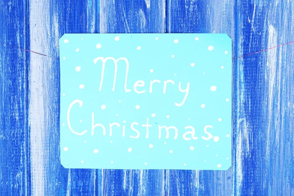 Bord met woorden vrolijk kerstfeest op blauwe houten tafel achtergrond close-up — Stockfoto