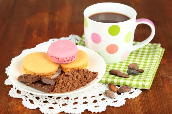 Cacao en taza con dulces y cacao en polvo en plato sobre mesa de madera —  Fotos de Stock